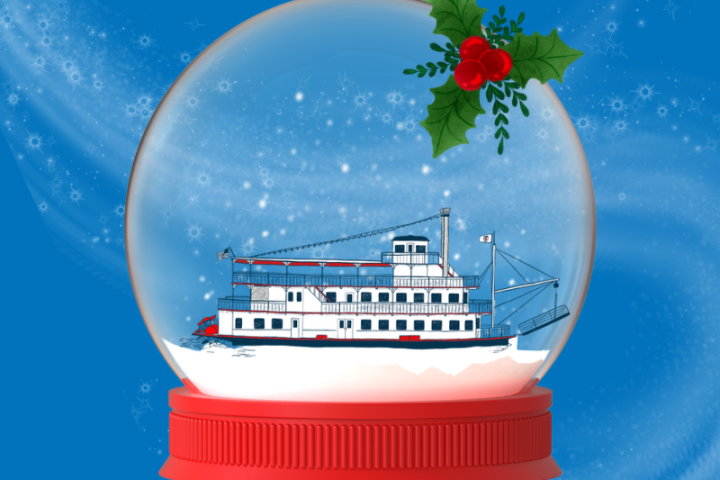 Snow globe with a steamboat inside, topped with holly, on a blue background.