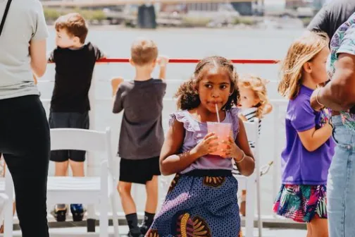 Children on a boat, skyline and bridge in background.