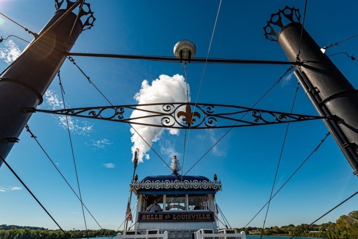 Steamboat Belle of Louisville with smoke puff, blue sky, and dark smokestacks.