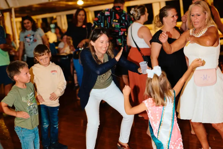 People dancing energetically in a lively indoor gathering with various age groups.