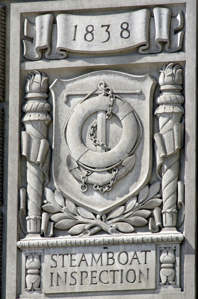 Stone relief carving titled 'Steamboat Inspection' with nautical symbols and '1838' inscription.